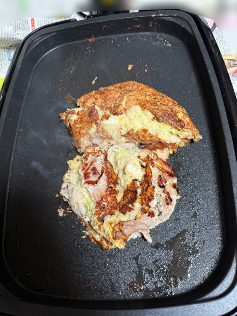 ホットプレートで豚肉をのせたお好み焼きを焼いているところ